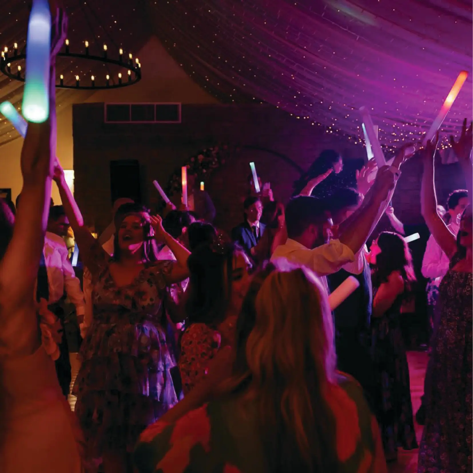 Wedding guests celebrating beneath fairy lights